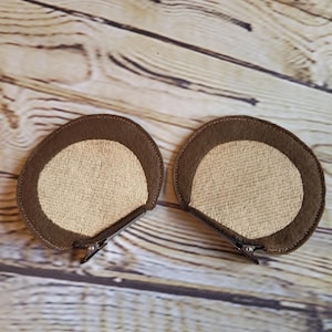 Può includere: Due fermagli per capelli in feltro marrone e beige, progettati per assomigliare a orecchie di animali. Il bordo esterno è marrone scuro, con un centro beige più chiaro. Ogni fermaglio ha una forcina metallica per fissare i capelli.