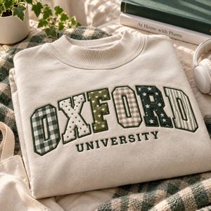 Puede incluir: Una sudadera de cuello redondo color crema con la palabra OXFORD en letras grandes de estilo bloque, cada una con un patrón único que incluye cuadros vichy verdes, lunares, corazones, tartán, estrellas y rayas, con la palabra UNIVERSITY debajo.