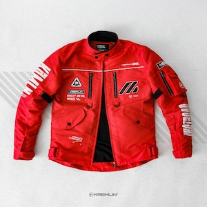 May include: A bright red motorcycle jacket featuring a high collar, black interior lining, and multiple zipped pockets. The jacket displays white graphic text including KREMLIN, RUSTY METAL WHEEL, and various technical symbols across the chest and sleeves.