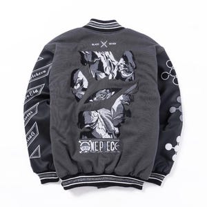Könnte beinhalten: Eine anthrazitfarbene Collegejacke mit schwarzen Ärmeln, die auf der Rückseite eine große Stickerei mit Anime-Figuren zeigt. Der Schriftzug "BLACK SEVEN" und "ONE PIECE" ist auf der Rückseite eingestickt, ergänzt durch weiße geometrische Muster.