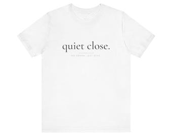 May include: A white short-sleeved t-shirt featuring the black text "quiet close." printed in a serif font on the chest, with the smaller text "NO DRAMA JUST KEYS" positioned directly below the main phrase, separated by a thin horizontal line.