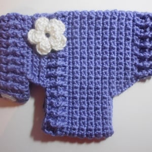 May include: A purple crocheted sweater with a white crocheted flower on the front.