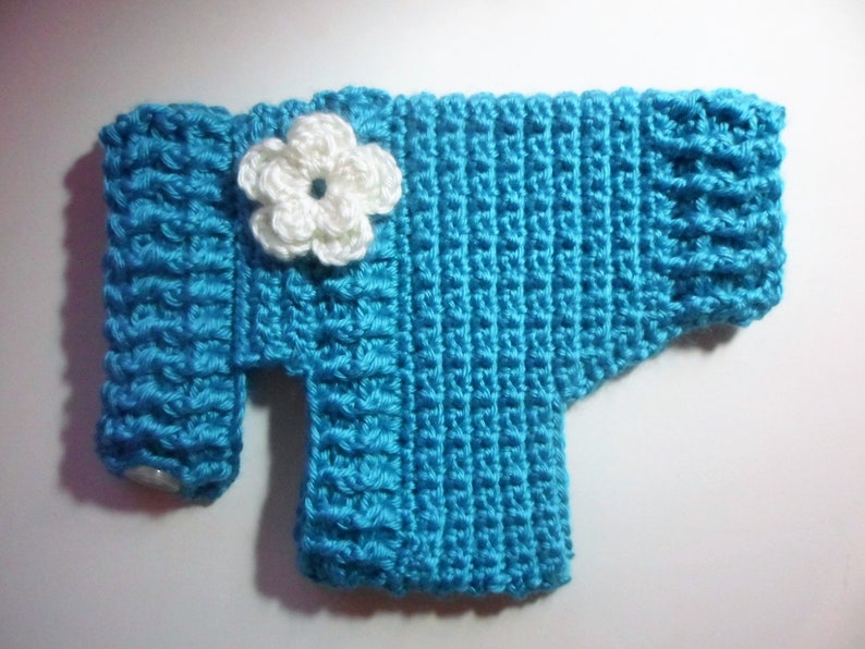 May include: A blue crocheted sweater with a white crocheted flower on the front.