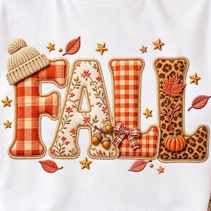 Puede incluir: Una camiseta blanca con la palabra FALL en letras grandes y estilizadas. La F tiene un gorro de punto beige, la A presenta motivos florales y bellotas, la L un patrón de cuadros con un lazo y la segunda L un estampado de leopardo con una calabaza.