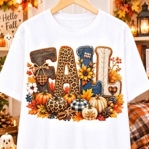 Può includere: Una t-shirt bianca con la parola FALL in grandi lettere. Ogni lettera ha una texture unica tra cui venature del legno, stampa leopardata, denim e maglia a trecce. Il design è decorato con zucche, girasoli, foglie e bastoncini di cannella.