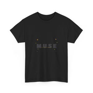May include: A black short-sleeve t-shirt featuring the word MUSE printed in dark grey block letters across the centre. A thin horizontal line runs through the text, accented by small yellow four-pointed stars and tiny coloured dots.