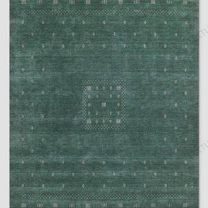 May include: A rectangular area rug in a deep teal green color featuring a central square motif composed of small white geometric shapes. The rug is bordered by horizontal bands of white dotted lines and repeating diamond and square patterns.