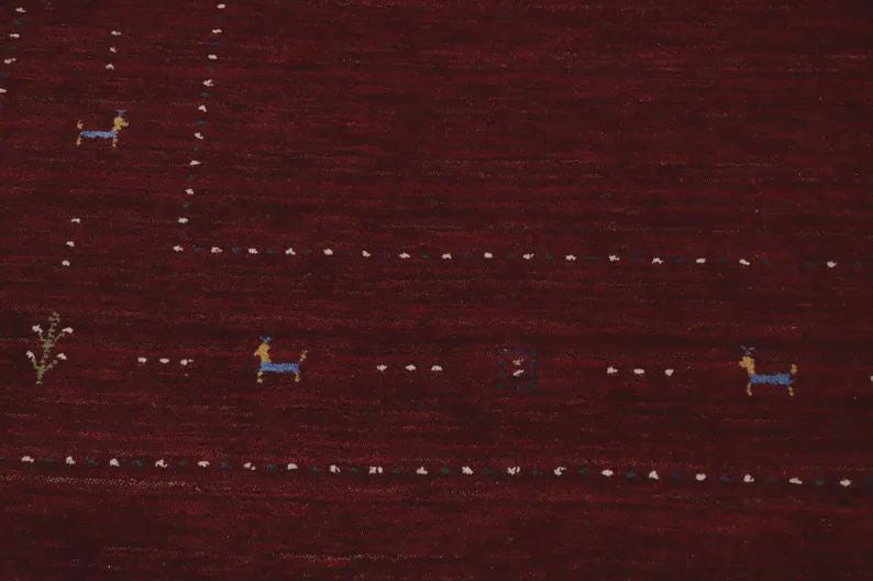 May include: A deep burgundy rug featuring a series of small, stylized blue animal figures and white dotted lines arranged in a geometric pattern. The design includes tiny green floral motifs interspersed among the animals on the dark red surface.