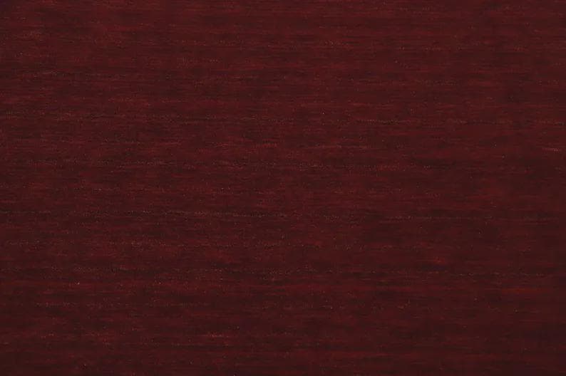 May include: A deep, dark burgundy wood grain texture featuring horizontal lines and subtle variations in color. The surface displays a smooth, polished finish with a consistent pattern of dark red and brown tones throughout the entire visible area.