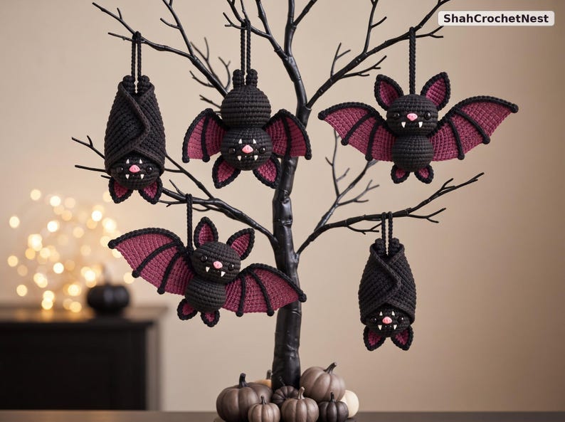 May include: Five handmade crochet bat ornaments in black and dark purple yarn, hanging from a black decorative tree. The bats feature small pink noses and white fangs. The text ShahCrochetNest is visible in the top right corner of the image.