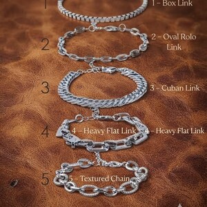 Könnte beinhalten: Fünf silberfarbene Armbänder, vertikal angeordnet und von 1 bis 5 nummeriert. Die Stile sind: 1-Box Link, 2-Oval Rolo Link, 3-Cuban Link, 4-Heavy Flat Link und 5-Textured Chain. Jedes Armband hat ein eigenes Metallgliederdesign und einen Verschluss.