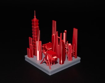 Op de afbeelding: Een 3D-geprint miniatuur stadssilhouetmodel in een levendige rode kleur, met diverse wolkenkrabberontwerpen en een klein bouwwerk met een traditioneel dak, alles gemonteerd op een vierkante grijze basis met gedetailleerde architecturale vormen.