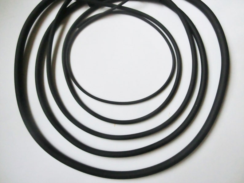 May include: Five black rubber bands of different sizes, arranged in a concentric circle pattern.