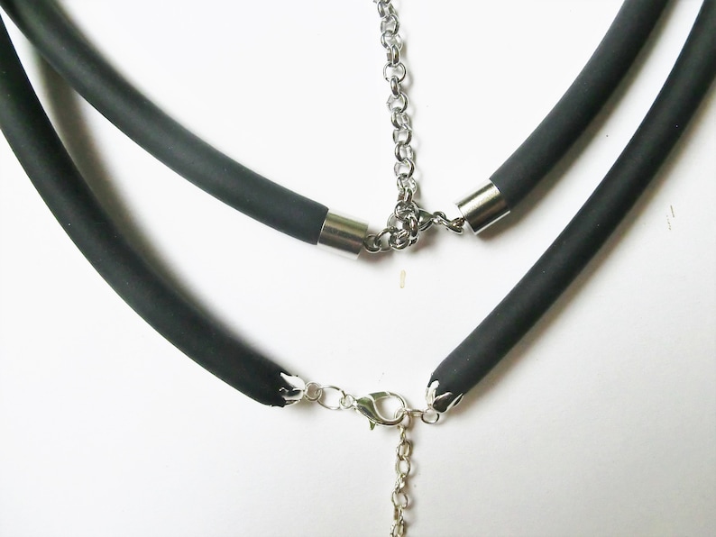 May include: A black rubber necklace with a silver chain and clasp. The necklace is made of two layers of rubber.