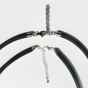 May include: Two black silicone necklaces with silver metal clasps and extension chains.