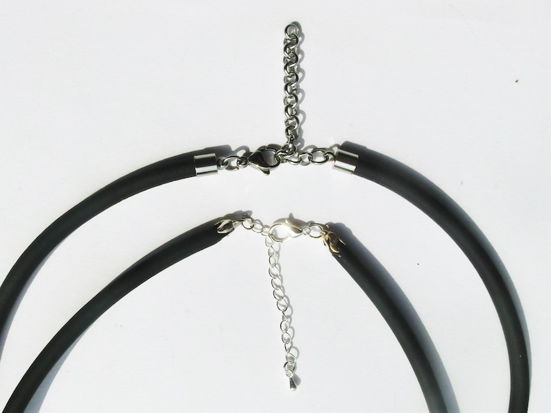 May include: Two black silicone necklaces with silver metal clasps and extension chains.