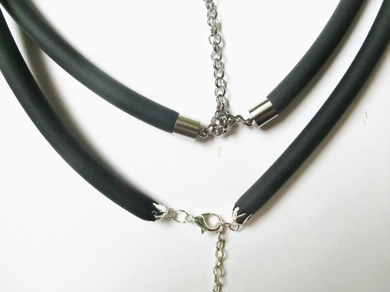 May include: A black rubber necklace with a silver chain and clasp. The necklace is made of two layers of rubber.