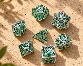 May include: A set of seven polyhedral dice featuring a silver-toned metal cage design with intricate leaf motifs and vibrant green enamel accents. Each die displays clear, embossed numbers, showcasing a detailed botanical theme across the collection.