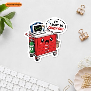 May include: A red medical crash cart sticker with a sad face, a green oxygen tank, and a heart rate monitor on top. A speech bubble above the cart contains the text I'M ABOUT TO CRASH OUT in black and red lettering. The design features a white border.