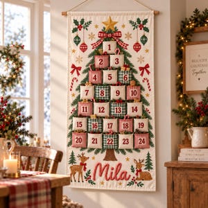 Può includere: Un calendario dell'Avvento in tessuto da appendere alla parete con un albero di Natale stampato e ventiquattro tasche numerate a quadri rossi e verdi. Il design include una stella dorata, decorazioni e il nome Mila ricamato in rosso.