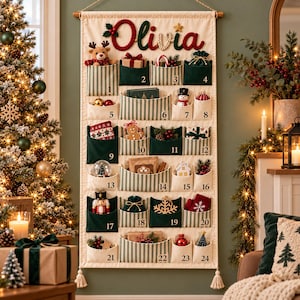 Peut inclure: Un calendrier de l'Avent mural en tissu avec vingt-quatre poches à rayures vertes et blanches ou en tissu vert uni. Le prénom Olivia est brodé en haut avec du fil rouge et vert. Chaque poche est numérotée de un à vingt-quatre.