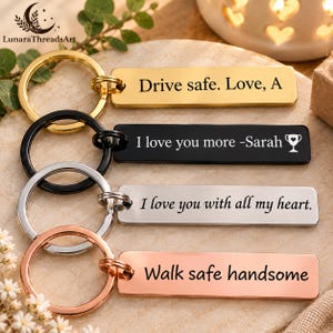 May include: Four rectangular metal keychains with circular rings in gold, black, silver, and rose gold tones. Each keychain features custom black engraved text: Drive safe. Love, A; I love you more -Sarah with a trophy icon; I love you with all my heart.; and Walk safe handsome.