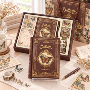 May include: A stationery gift set featuring a dark brown journal with a gold butterfly emblem and the text Butterfly, accompanied by matching note cards, a pen, decorative tape rolls, and a gift bag, all decorated with vintage butterfly motifs.