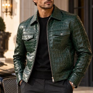 Pode incluir: Uma jaqueta verde-escura com textura brilhante de pele de crocodilo, apresentando gola pontiaguda, zíper de metal prateado em toda a extensão e dois bolsos no peito com abas abotoadas, usada sobre um suéter preto e calças pretas.