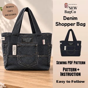 May include: A dark blue denim shopper bag with two top handles, multiple exterior pockets, and stitched detailing. The bag features a rectangular patch with text, a small side label, and a front pocket. The text reads SEW BagCo Denim Shopper Bag.