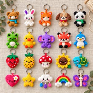 Könnte beinhalten: Eine Sammlung von zwanzig gehäkelten Schlüsselanhängern mit verschiedenen Tieren, Früchten und Formen, darunter ein Bär, Hase, Katze, Hund, Panda, Frosch, Ente, Elefant, Fuchs, Pinguin, Erdbeere, Ananas, Pilz, Sonnenblume, Schildkröte, Herz, Stern, Wolke, Regenbogen und Schmetterling.