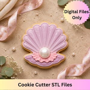May include: A seashell-shaped biscuit with light purple icing, a central white pearl, and a pink ruffled accent. The biscuit features a scalloped edge and a textured surface. Text on the image reads Digital Files Only and Cookie Cutter STL Files.