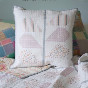 Pu&ograve; includere: Un copriletto bianco trapuntato con un motivo geometrico rosa e grigio. Un cuscino bianco con un motivo geometrico rosa e grigio &egrave; sul letto.