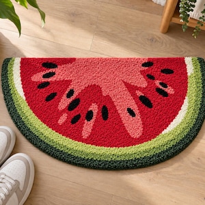 Può includere: Un tappeto trapuntato a semicerchio a forma di fetta di anguria. Il tappeto presenta un centro rosso brillante con forme di semi neri, una sottile buccia bianca e un bordo esterno spesso in fibre testurizzate verde chiaro e scuro.