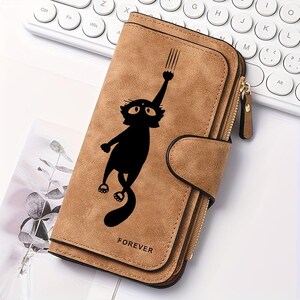 May include: A tan, rectangular, bi-fold wallet featuring a black graphic of a cat reaching upward with one paw. The wallet has a snap-button closure, a side zipper compartment, and the word FOREVER embossed in small black letters at the bottom.