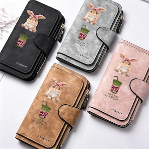 May include: Four rectangular wallets in black, gray, tan, and pink. Each features a graphic of a bunny with a pink bow and a green matcha drink with the text I LOVE YOU SO MATCHA. The word FOREVER is printed near the bottom of each wallet.