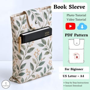 May include: A fabric book sleeve with a cream background and a green leaf and yellow berry pattern, featuring a snap closure flap, a front pocket containing a black 2024 notes notebook and a gold pen, with text including Book Sleeve, PDF Pattern.