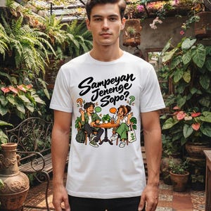 Könnte beinhalten: Ein weißes kurzärmeliges T-Shirt mit einer grafischen Illustration von zwei Personen, die an einem runden Tisch mit Getränken sitzen. Über der Illustration steht der schwarze Text "Sampeyan Jenenge Sopo?" neben orangefarbenen und grünen Sprechblasen.