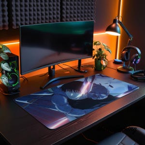 Peut inclure: Un tapis de bureau rectangulaire présentant une illustration anime aux tons bleus d'un personnage aux cheveux sombres et à la silhouette musclée. Le tapis est posé sur un bureau en bois sombre devant un écran incurvé, une enceinte et une lampe.