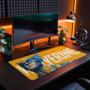 Op de afbeelding: Een rechthoekige bureaumat met een grafische illustratie van het stripfiguur Wolverine in een blauw en geel kostuum, met de tekst "WOLVERINE" in grote witte letters gedrukt op een levendige gele achtergrond.