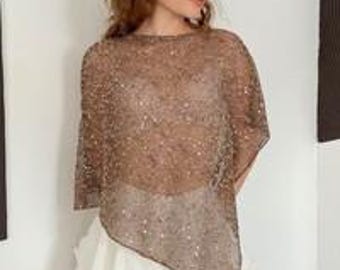 May include: A sheer, brown, sequined poncho with a loose, asymmetrical drape and short sleeves, paired with a white, tiered, ruffled mini skirt and a beige, open-weave, skullcap-style head covering with a grid pattern.