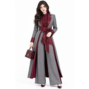 Könnte beinhalten: Ein langärmeliger grauer Mantel mit breitem Revers und einer tiefroten Satin-Schärpe, die in der Taille gebunden ist. Der Mantel hat weinrote Satin-Manschetten und eine passende weinrote Bluse darunter. Eine kleine, strukturierte Handtasche.