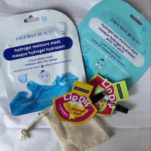 May include: A collection of Freeman Beauty skincare products including a white hydrogel moisture face mask, a light blue hydrogel eye moisture mask, two small yellow and pink Lip Dip sleeping mask and scrub pouches, and a small beige mesh drawstring bag.