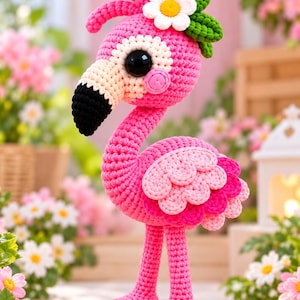 Puede incluir: Una figura de flamenco tejida a ganchillo con cuerpo rosa brillante, pico negro y grandes ojos negros. La cabeza está adornada con una margarita blanca y hojas verdes. Las alas están superpuestas con hilo rosa claro y oscuro, sobre dos patas rosas.