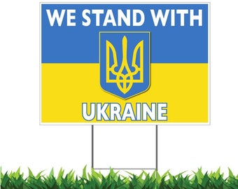 May include: A blue and yellow sign with the text "WE STAND WITH UKRAINE" and the Ukrainian coat of arms in the center.