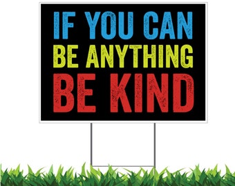 May include: A black yard sign with white lettering that reads "If you can be anything be kind". The words "If you can" are in blue, "be anything" are in yellow, and "be kind" are in red.