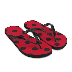 May include: A pair of red flip-flops with black polka dots. The flip-flops have a black thong strap.