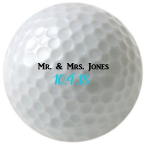 Puede incluir: Bola de golf blanca con texto negro que dice "Mr. & Mrs. Jones 10.4.18"