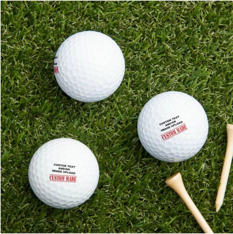 Puede incluir: Tres bolas de golf blancas con texto negro y un sello rojo que dice "CUSTOM MADE". El texto en las bolas dice "CUSTOM TEXT AND/OR IMAGE UPLOAD".