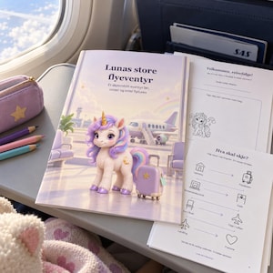 Pu&ograve; includere: Un libro di attivit&agrave; per bambini intitolato Lunas store flyeventyr con un unicorno dai crini viola e una piccola valigia. La copertina mostra una scena aeroportuale con un aereo. Accanto ci sono matite colorate e un astuccio viola.