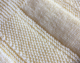 May include: A pale yellow knitted baby blanket with a textured stitch pattern.